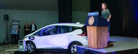 Electric vehicle with speaker at a podium.